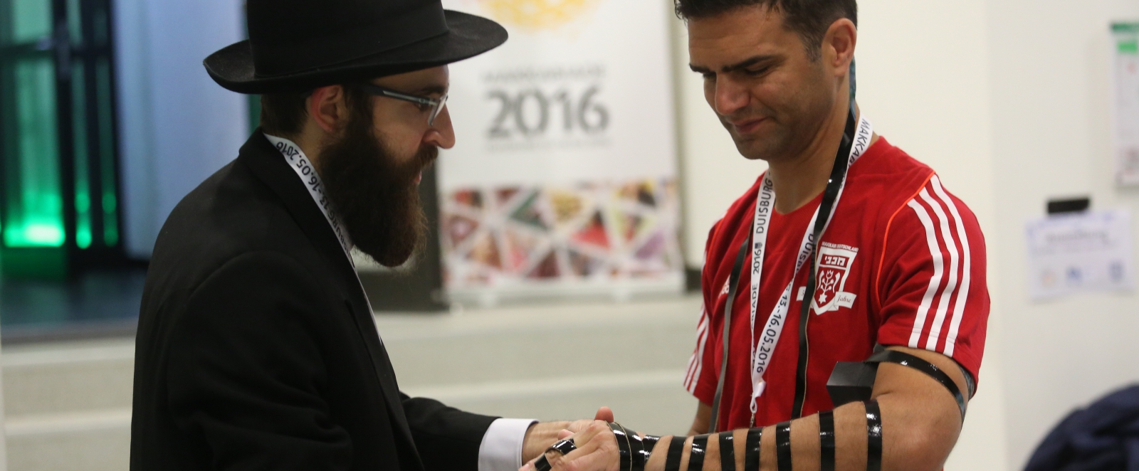 Ein Rabbiner mit einem Athleten im roten Trikot im Gespräch.