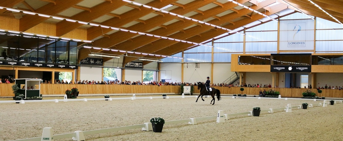 Eine Dressur Reiterin mit ihrem Pferd in einer Halle auf einem Sandplatz