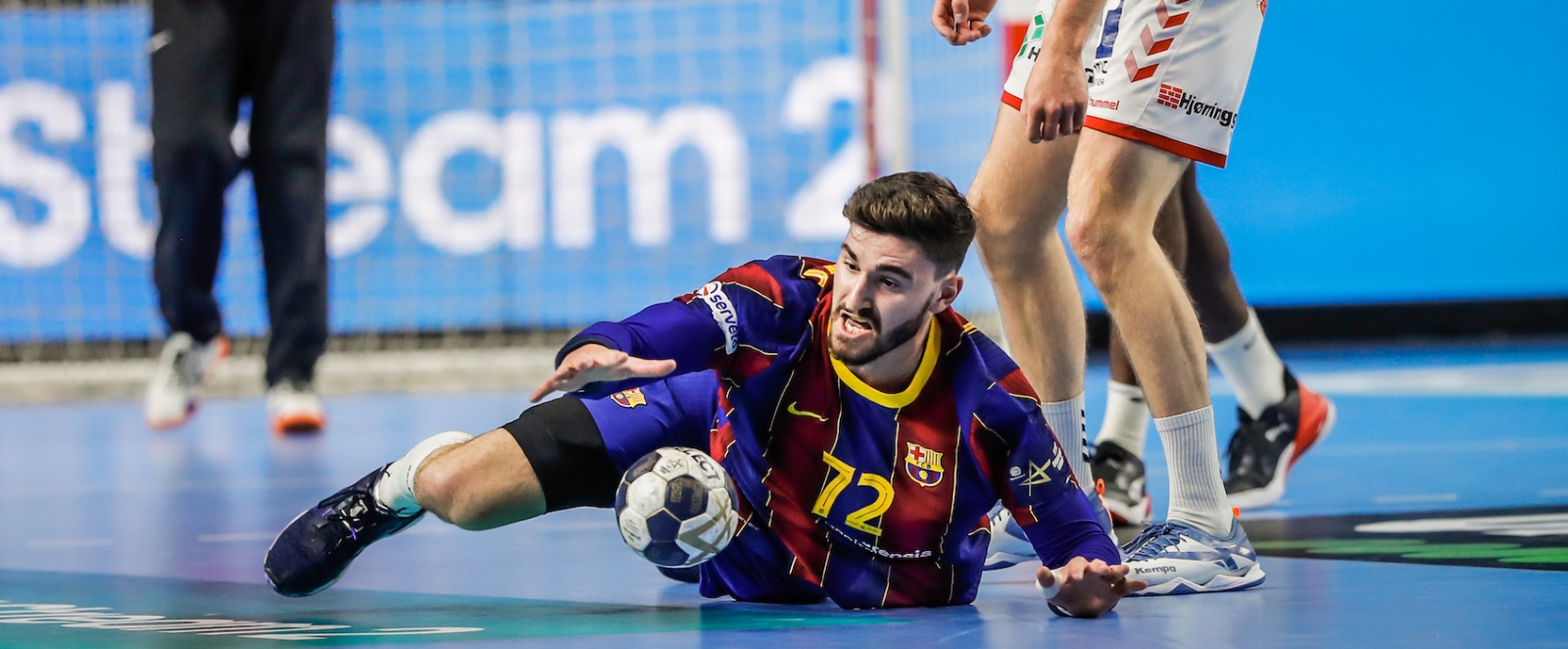 Barcelona Spieler liegt auf dem Boden und greift nach dem Handball