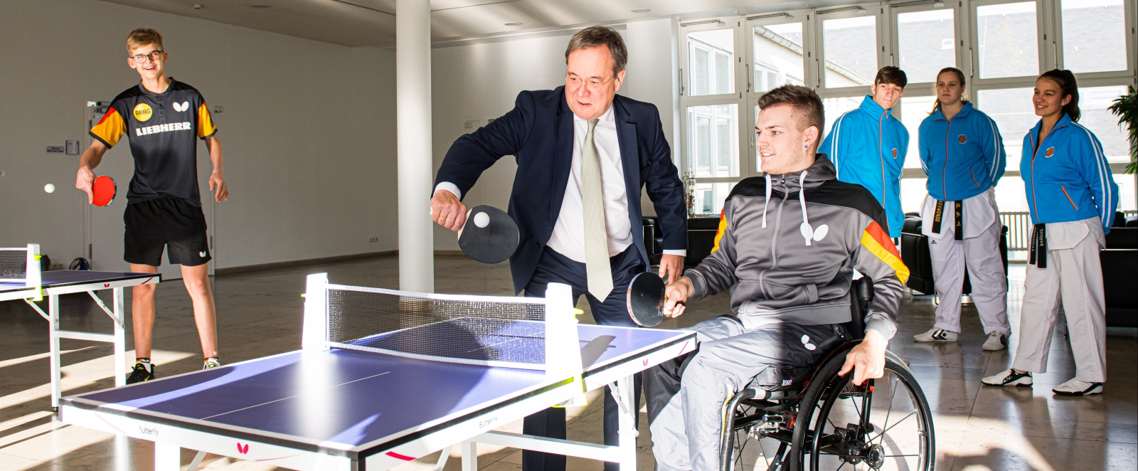 Armin Laschet spielt mit einem jungen Sportler im Rollstuhl Tischtennis.