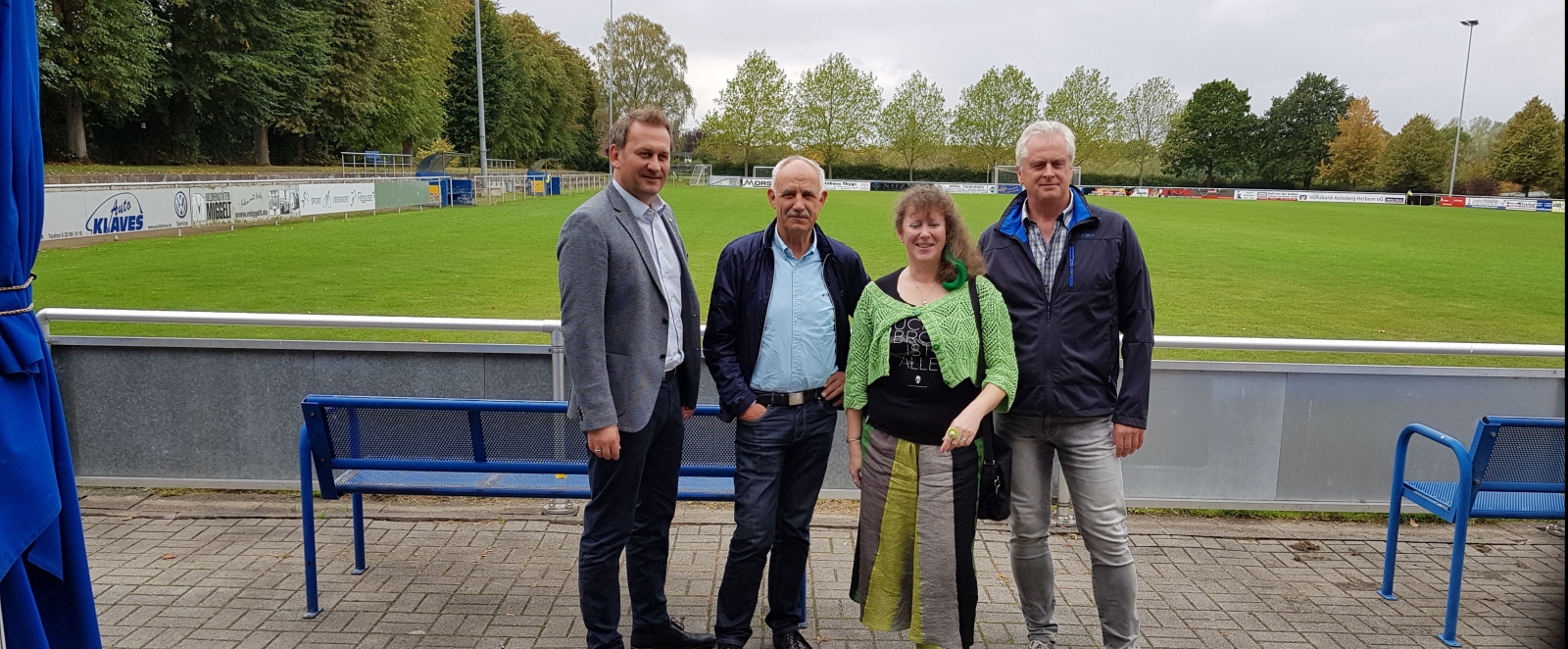 Staatssekretärin Andrea Milz mit Mitgliedern des SV Herbern vor einem Rasen-Fußballplatz.