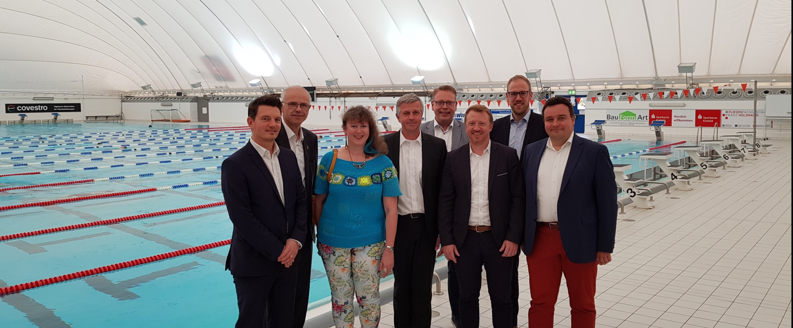 StaaGruppenfoto von tssekretärin Milz mit Vereinsmitgliedern in einer Schwimmhalle.