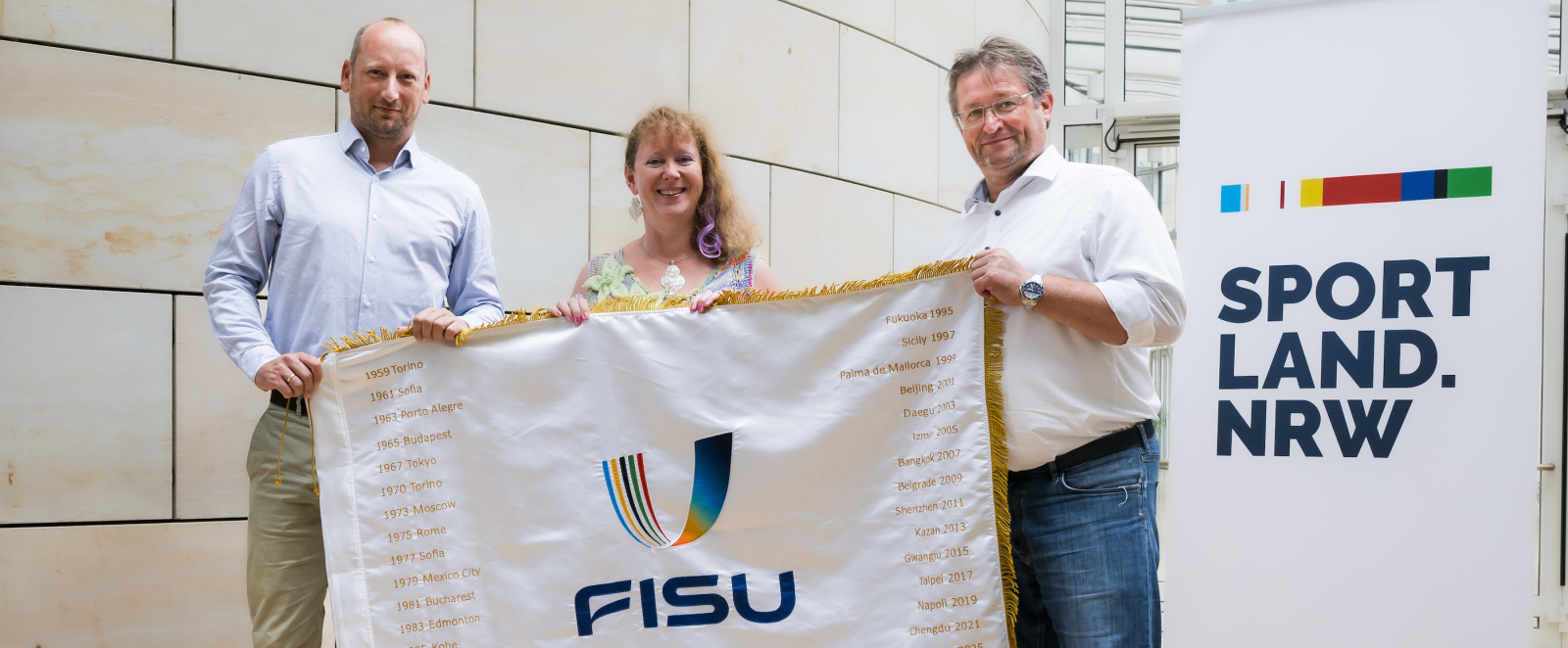 Andrea Milz und zwei Männer mit FISU-Flagge