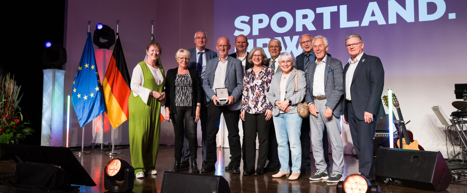 Andrea Milz mit weiteren Personen vor Sportland.NRW-Banner