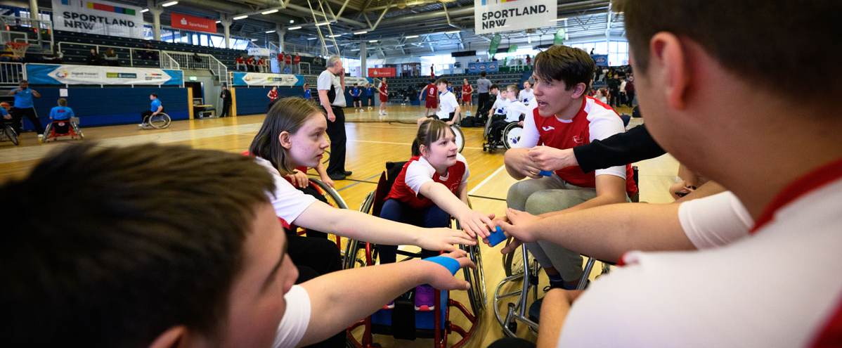 Rollstuhlbasketballspieler in einem Kreis in der Halle