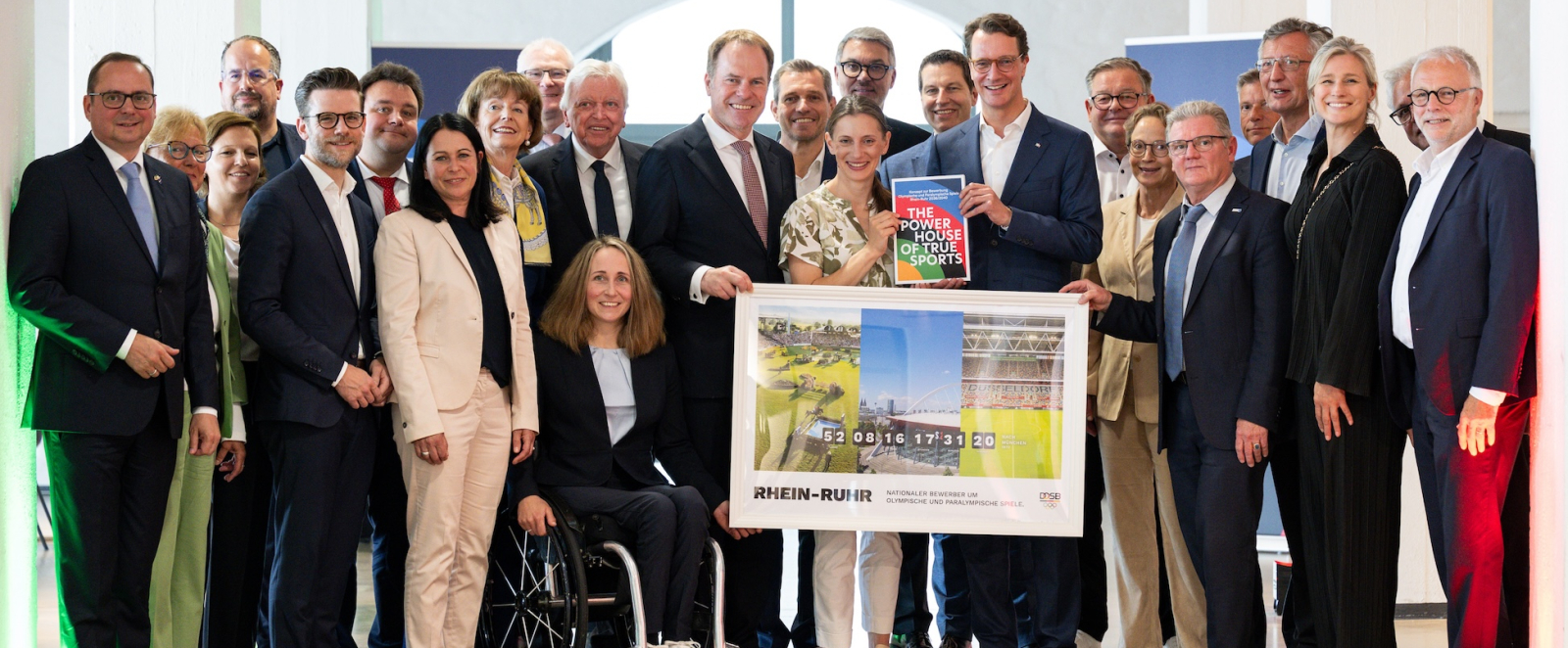 Ministerpräsident Wüst mit weiteren Personen auf einer Bühne