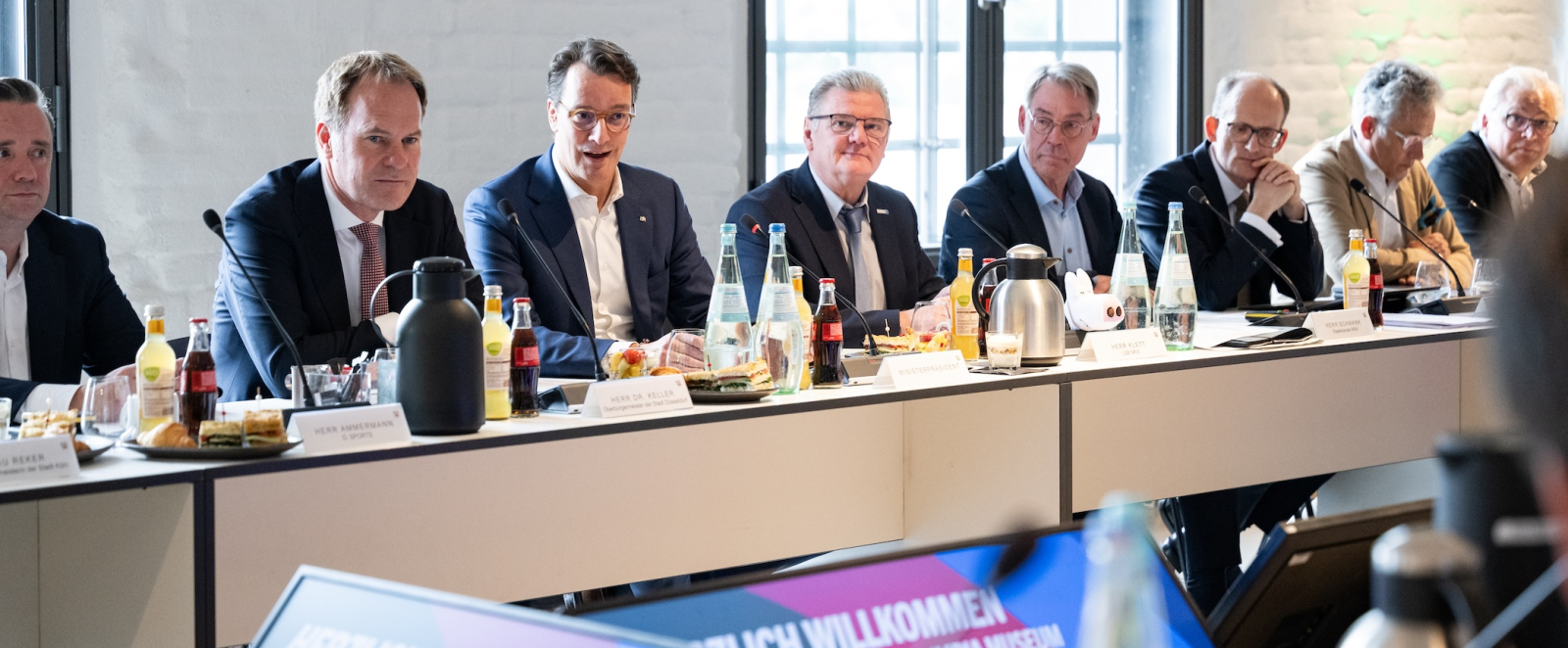 Ministerpräsident Wüst und weitere Personen bei der Pressekonferenz an Tischen