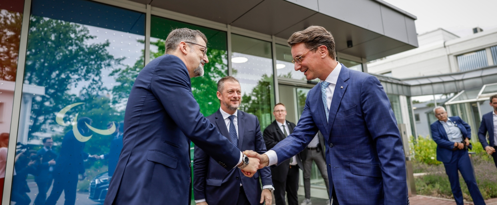 Hendirk Wüst und ein weitere Mann geben sich bei der IPC Eröffnung in Bonn die Hände