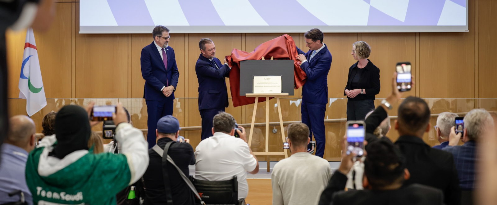 4 Menschen heben einen Vorhang von einer Tafel runter