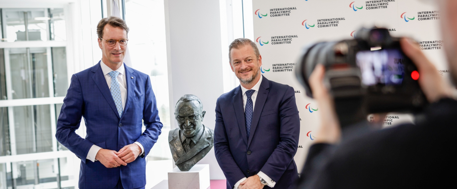 Hendirk Wüst und ein weitere Mann stehen zwischen einer kleinen Statur 