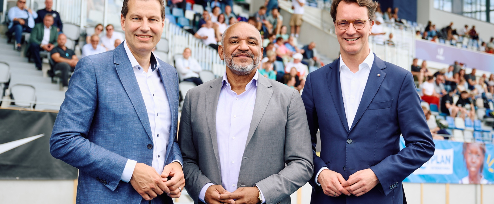 Hendrik Wüst mit zwei weiteren Personen im Stadion