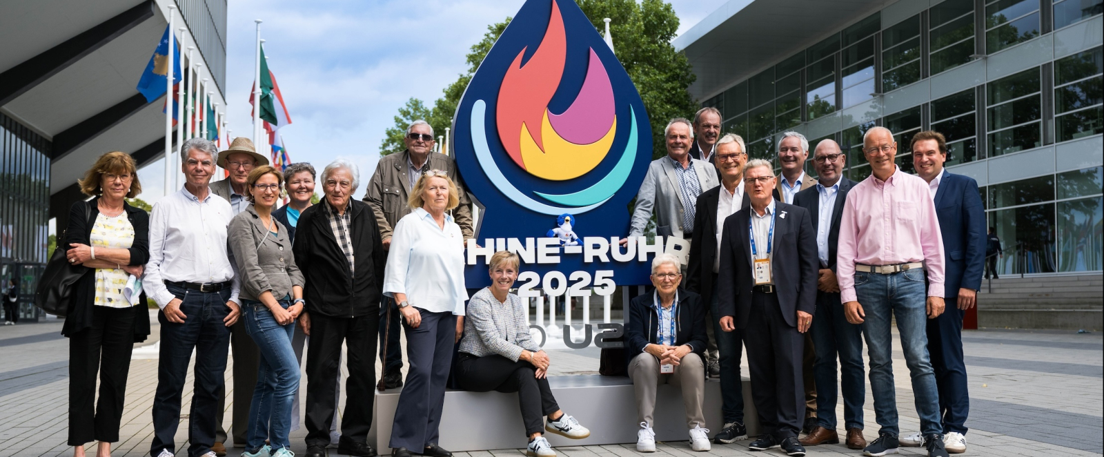 Menschen vor dem RR25-Logo und zwischen zwei Gebäuden
