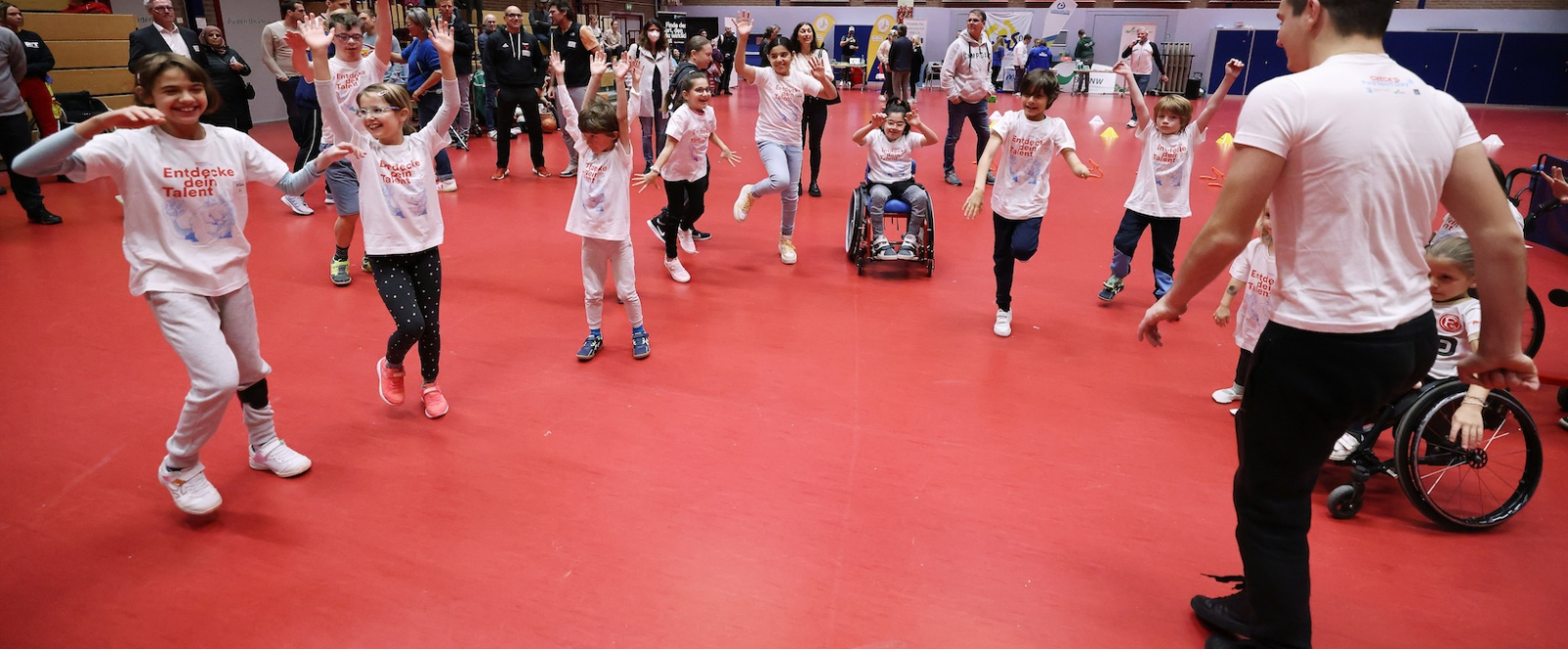 Gruppe von Kindern in einer Halle mit rotem Boden