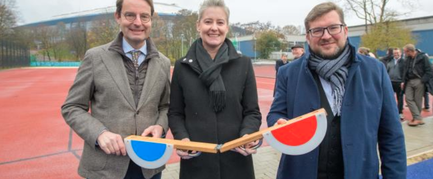 Drei Personen stehen vor einer roten Tartanbahn