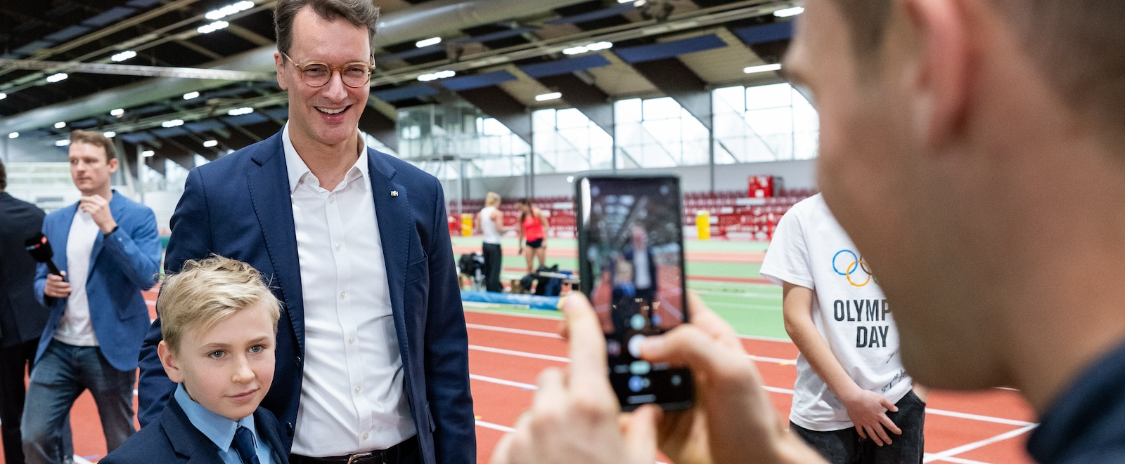Mann macht von Hendrik Wüst und Jugendlichen ein Foto mit dem Smartphone 