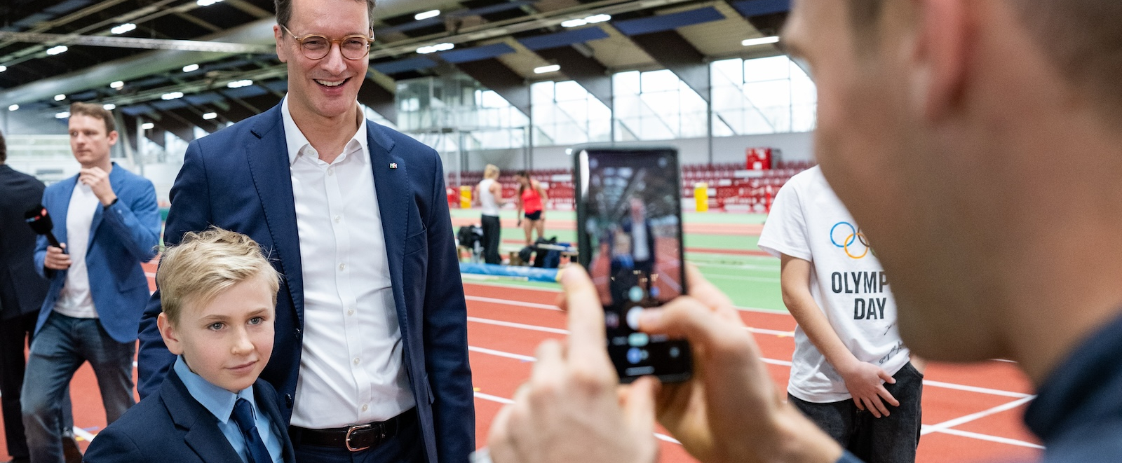 Mann macht von Hendrik Wüst und Jugendlichen ein Foto mit dem Smartphone 