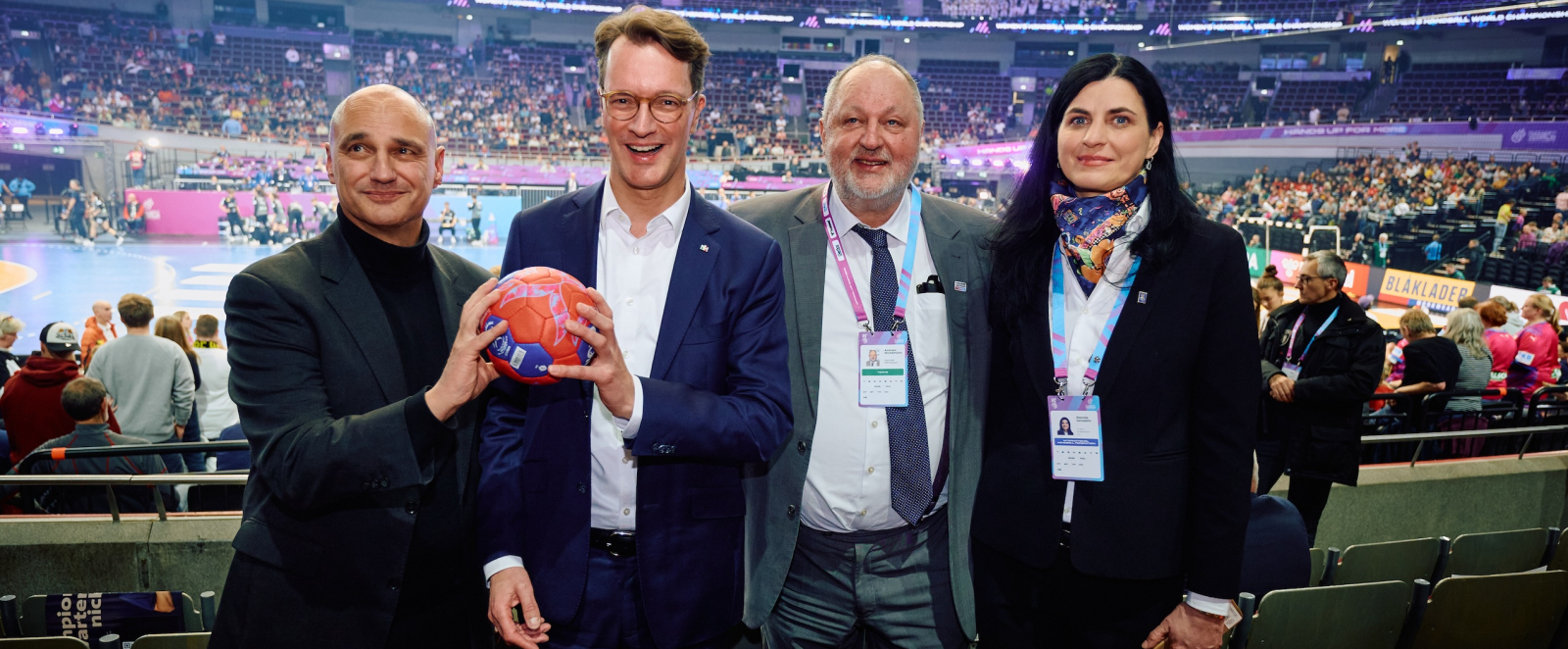 Hendrik Wüst und drei weitere Personen beim Handball-Spiel in der Halle