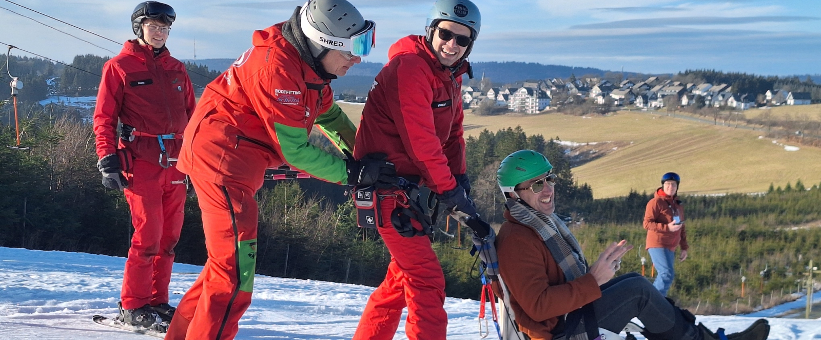 Rot gekleidete Personen schieben eine weitere Person in einem Schlitten