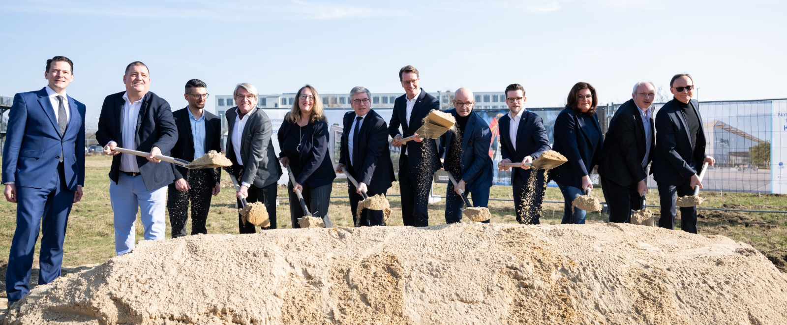 Wüst mit mehreren Personen mit Spaten auf einem Erdhaufen 