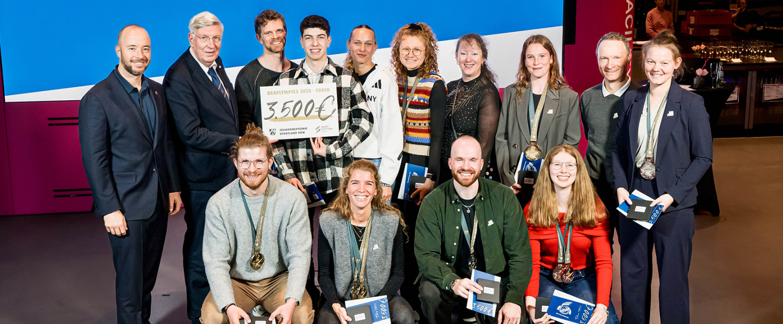 Mehrere Personen in zwei Reihen vor einem blauem Banner mit der Aufschrift 45.500 Euro