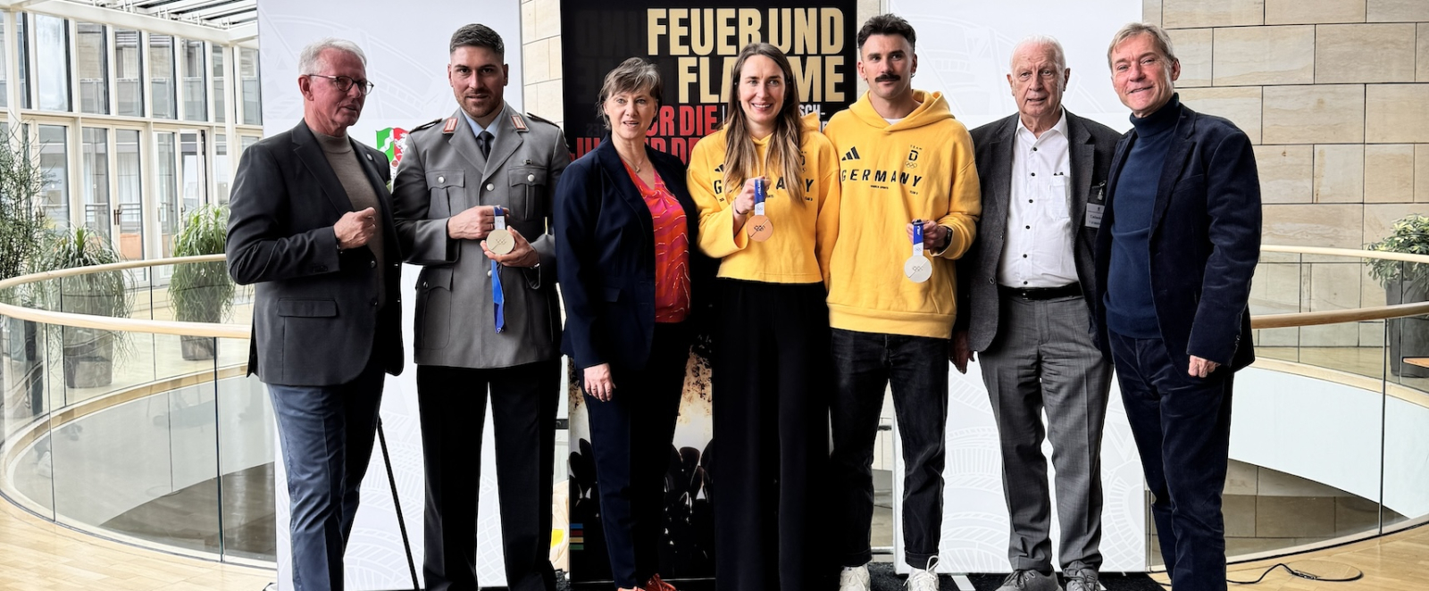 Mehrere Personen auf einem schwarzen Podium bei der Ausstellungseröffnung im Landtag NRW