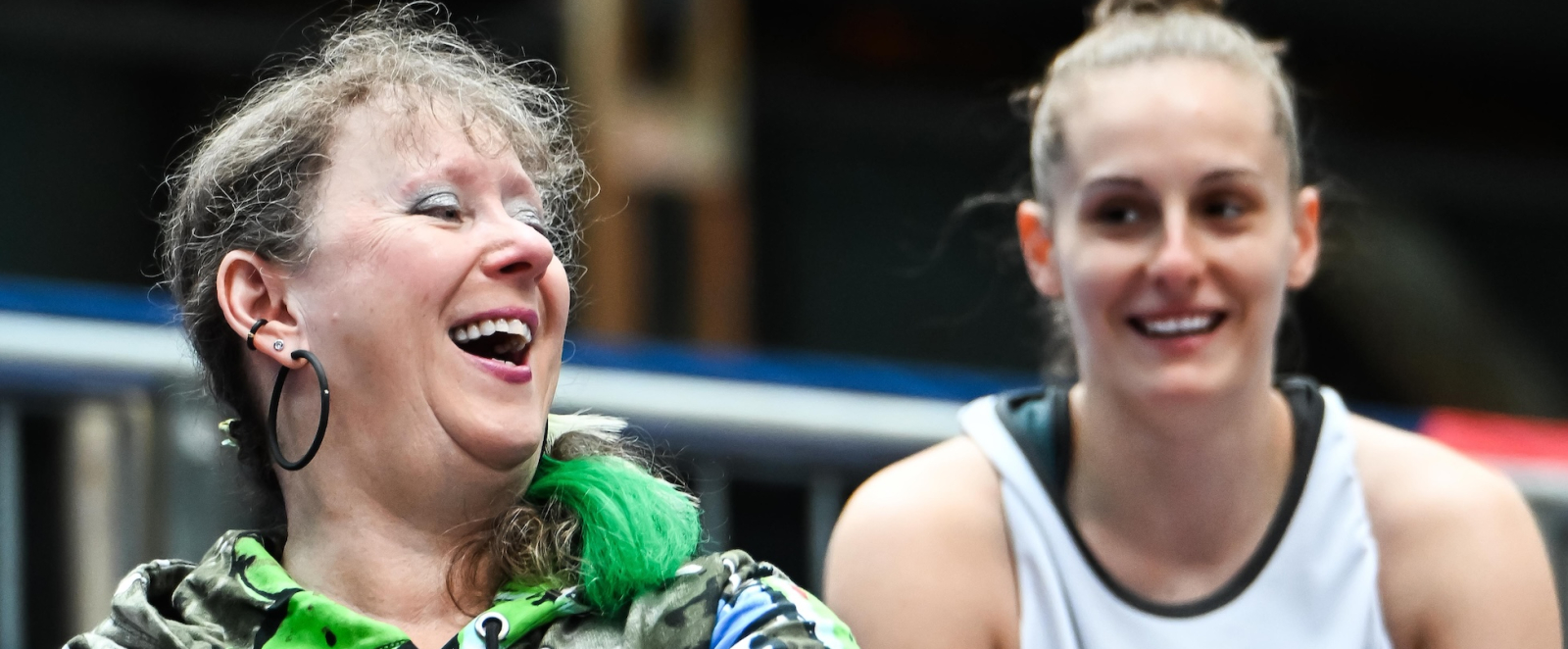 Lachende Andrea Bowinkelmann neben einer 3x3-Spielerin auf der Tribüne