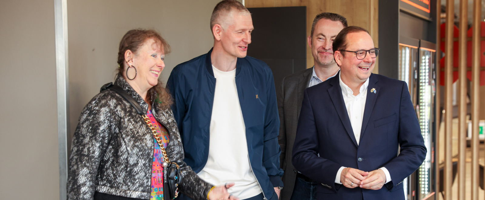 Andrea Milz im Gespräch mit drei Männern, im Hintergrund ein Fitnesstudio