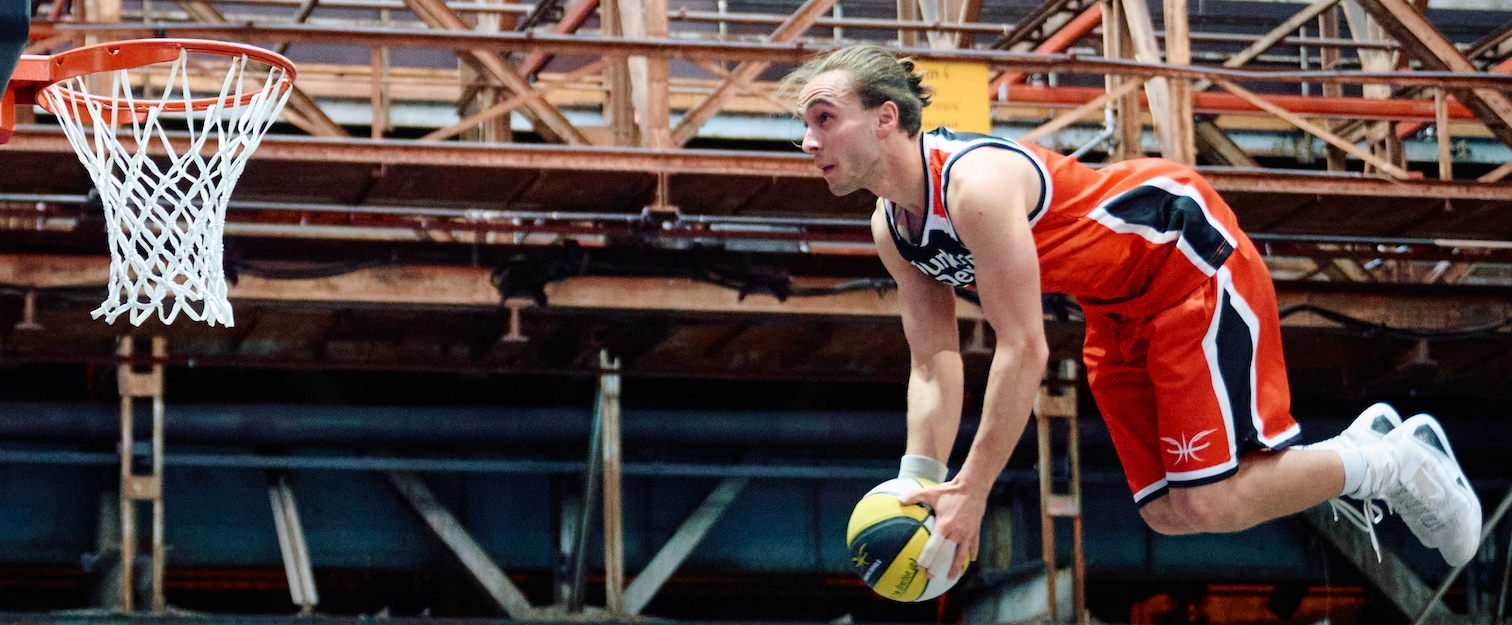 3x3-Spieler in rotem Trikot in der Luft vor dem Korb