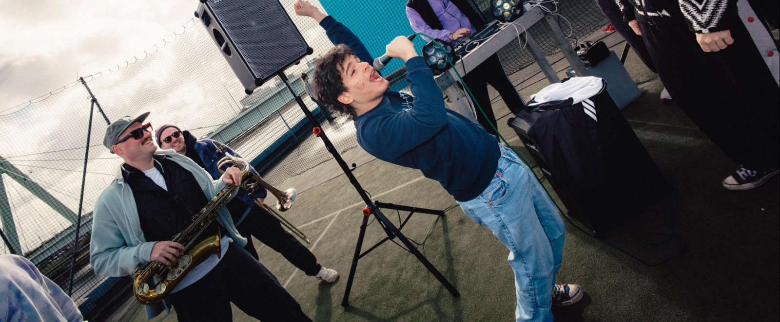 Ein Sänger performt, Bandmitglieder stehen lächeln um ihn herum