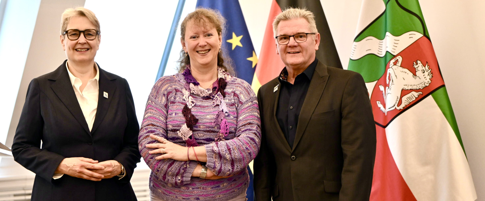 Andrea Milz neben Stefan Klett und Gabriela Pantring vor drei Fahnen
