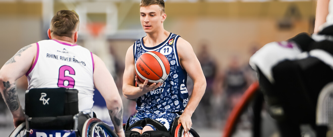 Maximilian Lammering in einem Rollstuhl dribbelt einen Basketball