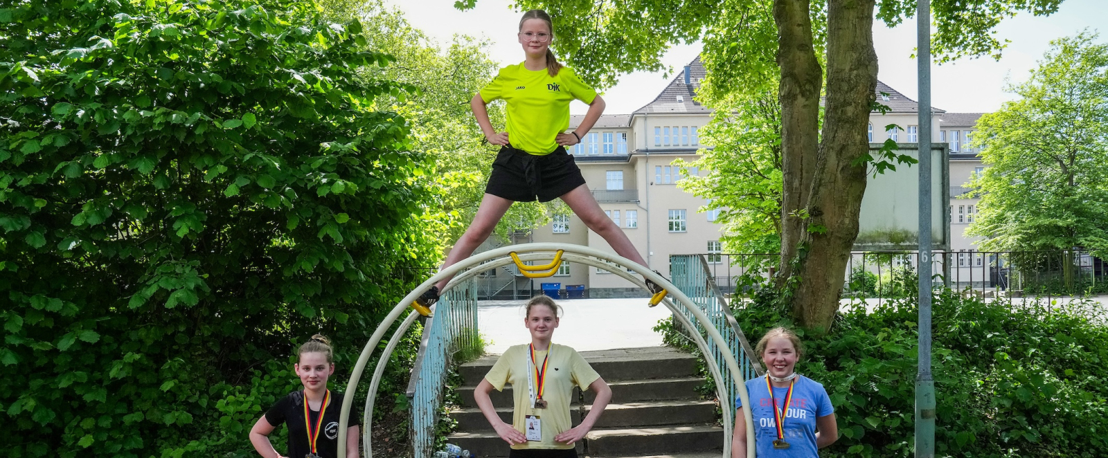 Vier junge Athletinnen in einem Rhönrad mit Medaillen um den Hals, eine Athletin steht auf dem Rhönrad