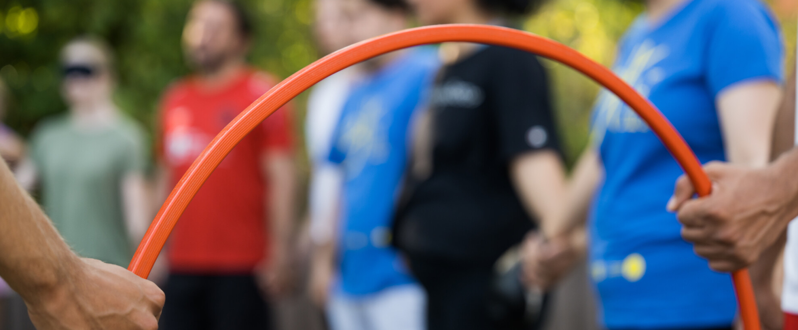 Junge Menschen, im Vordergrund ein roter Reifen, der von zwei Händen gehalten wird