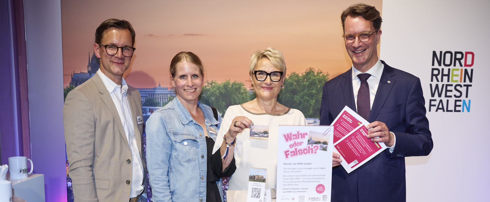 Hendrik Wüst neben weiteren Personen mit Quizfragen-Karten in der Hand