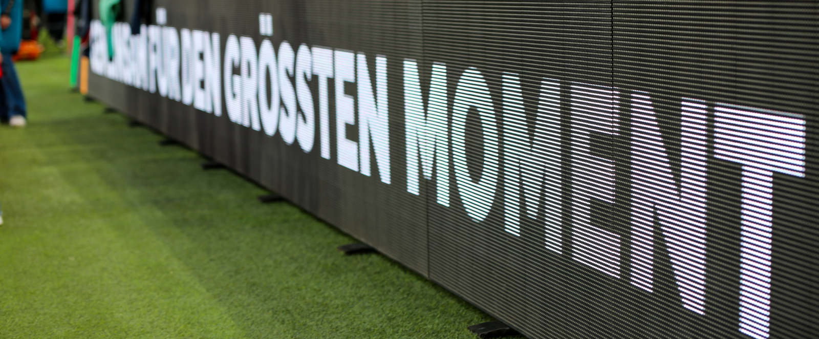 Banner am Fußballplatz-Rand mit der Aufschrift "für den größten Moment"