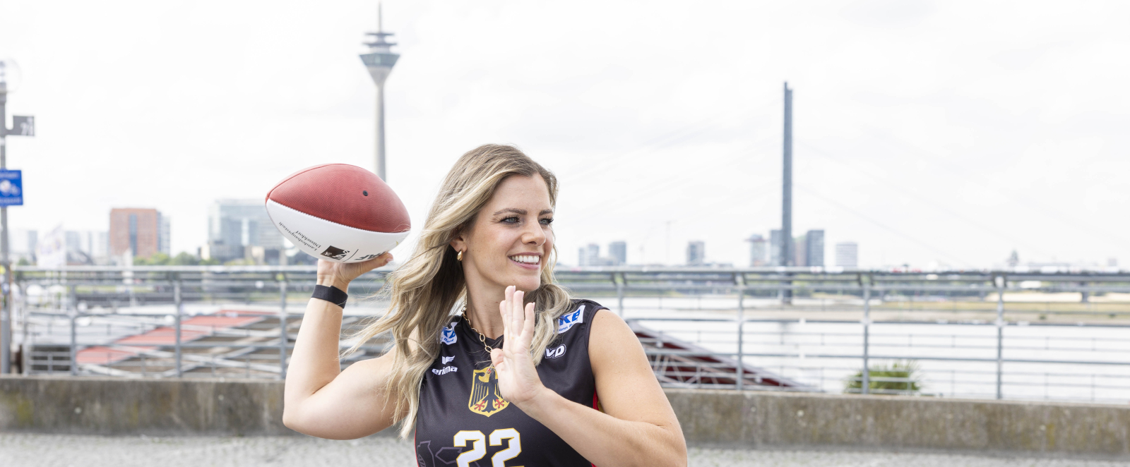 Athletin vor der Düsseldorfer Skyline mit einem Football
