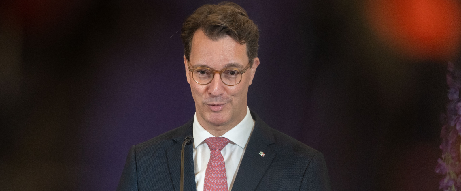 Ministerpräsident Wüst an einem Rednerpult vor dunklem Hintergrund