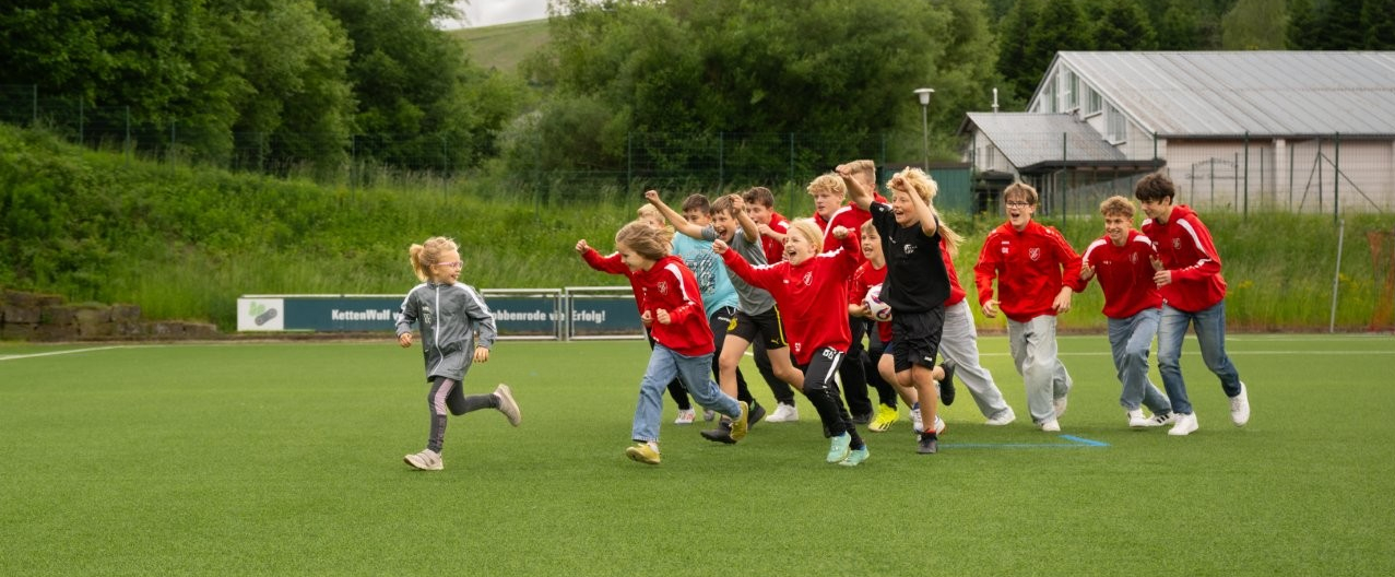 Gruppe von Jugendlichen läuft über eine Fußballplatz