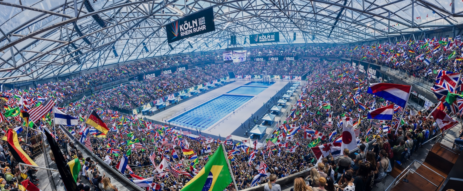 KI-Bild der Veltins Arena bei Olympischen Spielen mit einem Schwimmbecken in der Mitte und Fans drumherum