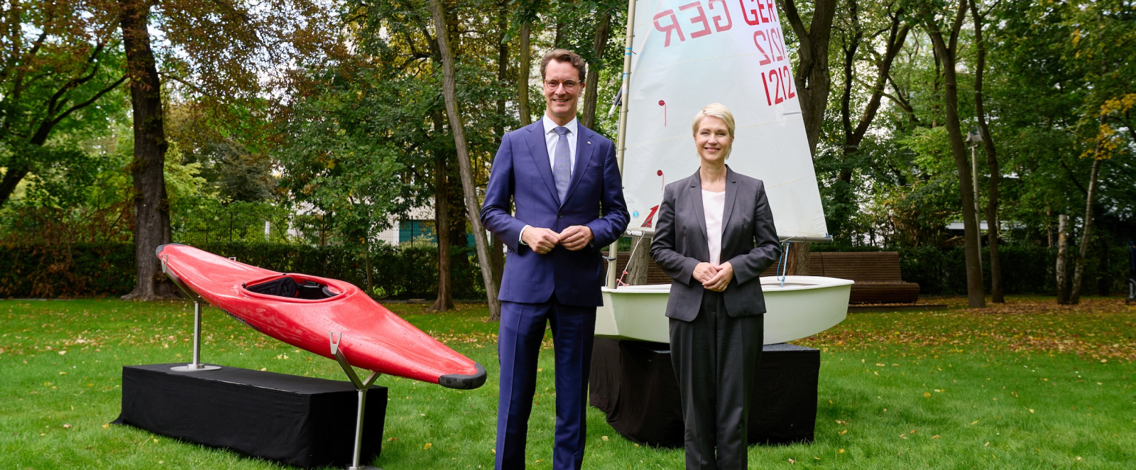 Ministerpräsidenten Schwesig und Wüst mit einem Kanu und einem Segelboot im Hintergrund