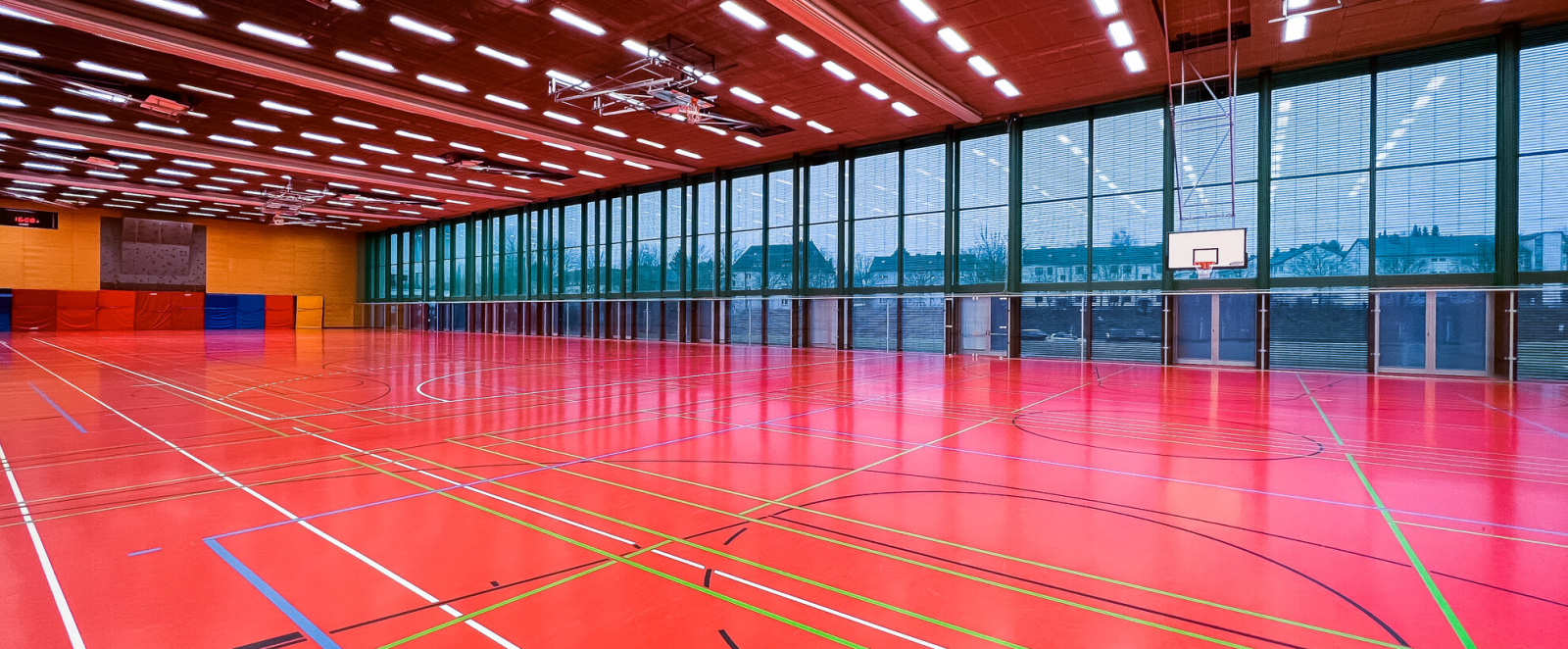Blick in eine leere Sporthalle mit roten Boden