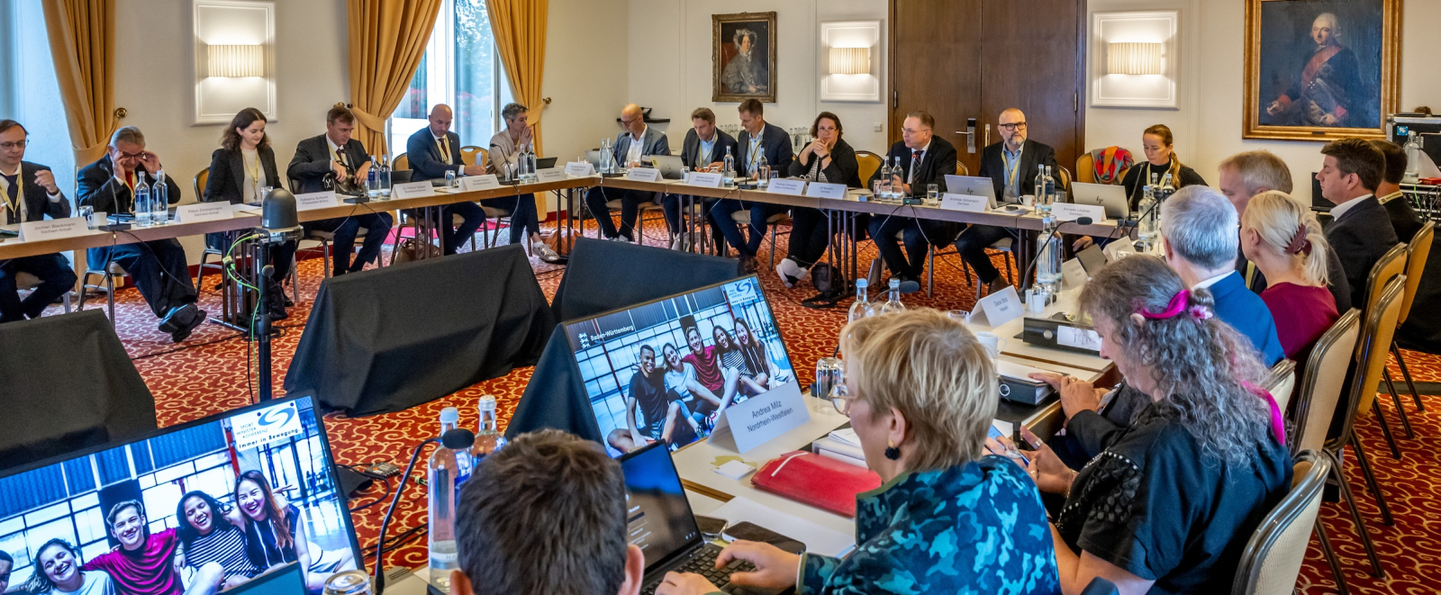 Blick auf einen Konferenzraum mit vielen Personen an Tischen