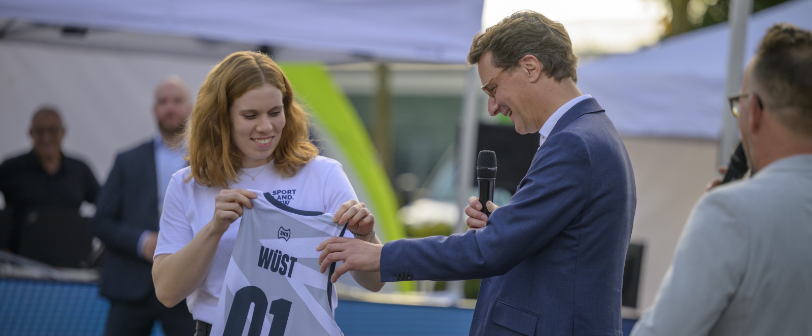 Hendrik Wüst überreicht ein Trikot