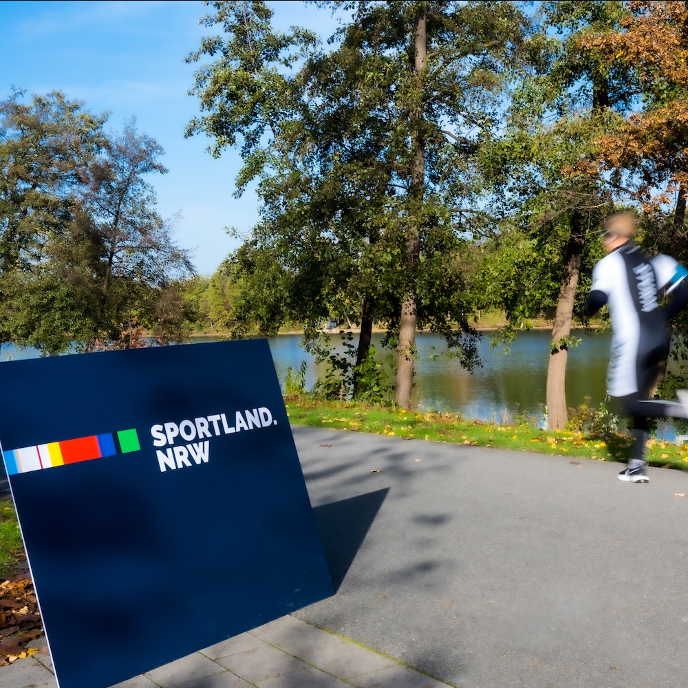 Jogger mit Sportland.NRW-Schild
