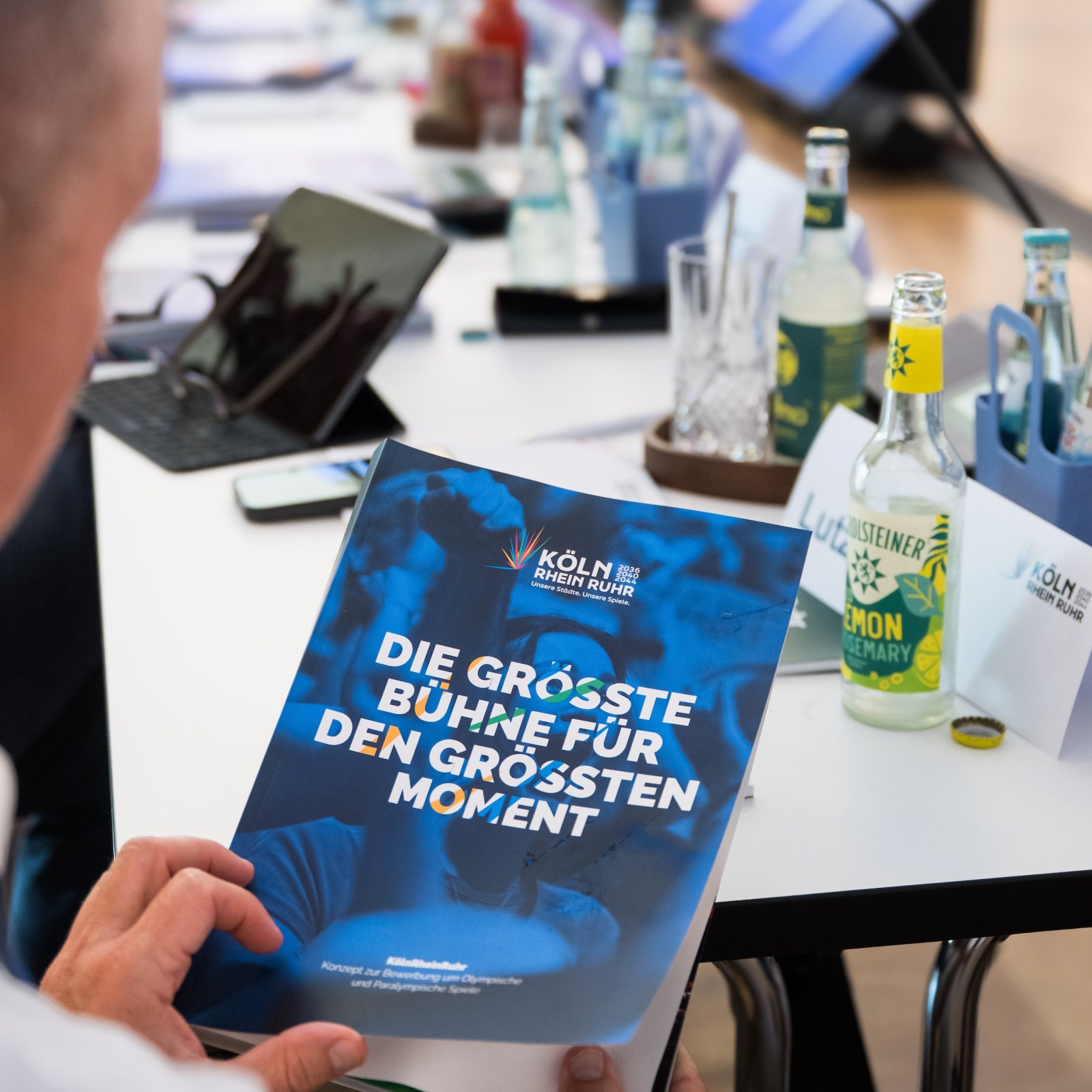 Mannn im Profil blättert im Booklet KölnRheinRuhr, im Hintergrund ein langer Arbeitstisch