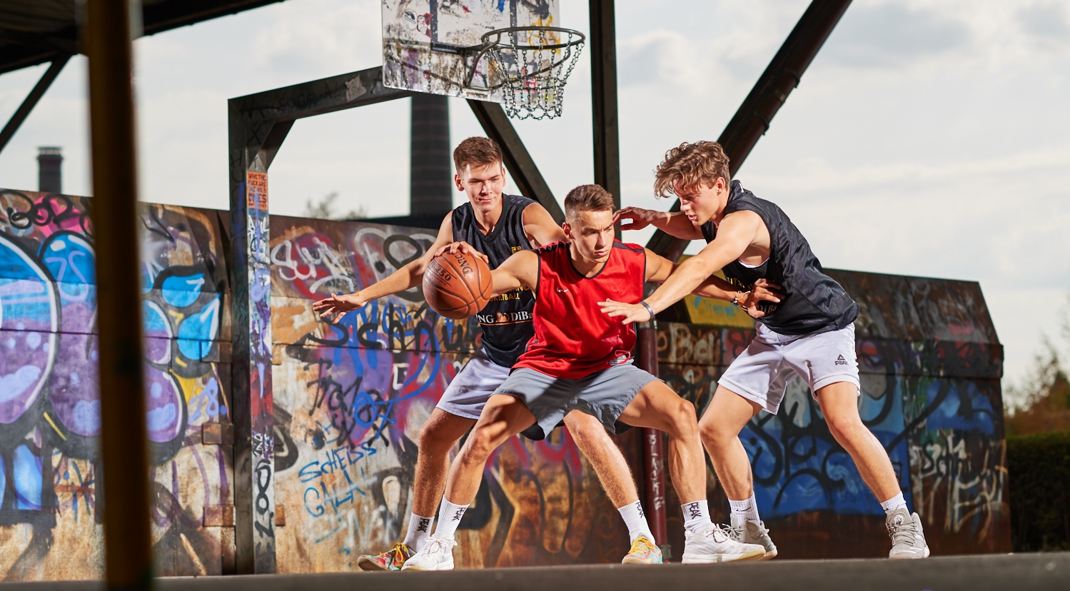 3 Sportler spielen Basketball 