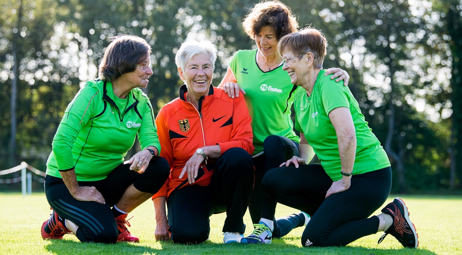 Seniorinnen machen gemeinsam Sport auf einer Rasenfläche