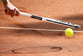Tennisschläger und Ball auf roter Asche