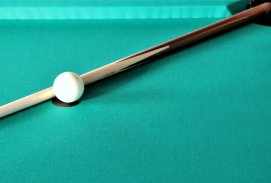 weiße Billardkugel auf einem grünen Billardtisch und einem Queue