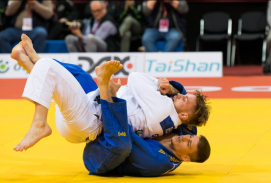 zwei Judoka kämpfen auf einer gelben Matte